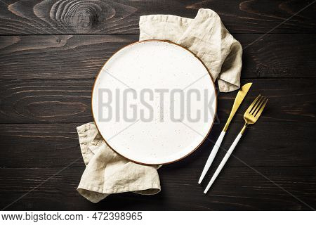 White Plate With Luxury Cutlary At Dark Wooden Table. Top View With Copy Space.