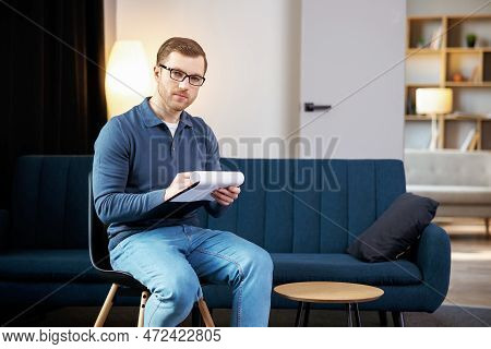 Portrait Of Happy Male Psychologist Looking At Camera And Taking Notes During Therapy Session At Cli