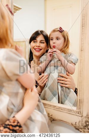 A Cute Little Girl In A Plaid Dress And Mom Primping.