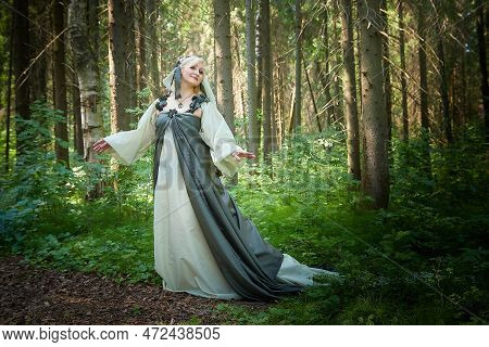 Adult Mature Woman 40-60 In A Green Long Fairy Dress In Forest. Photo Shoot In Style Of Dryad And Qu