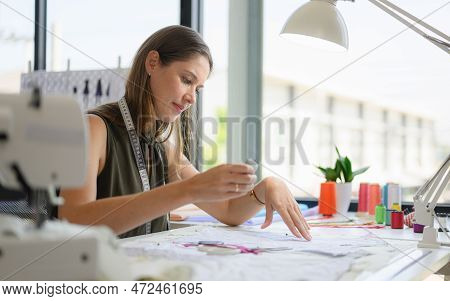Happy Female Dressmaker Working In Workshop Studio