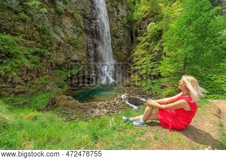 Woman Resting After Trekking In The Forest Of Sonogno To Froda Waterfall By The Riale Carded River. 