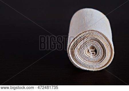 Dirty, Used Medical Elastic Bandage On A Dark Background. Twisted Into A Roll. Concept Of Medicine. 