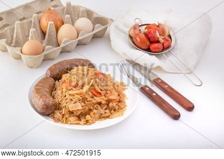 Braised Cabbage - Bigos And Grilled Sausage In A White Porcelain Plate Against The Background Of Chi