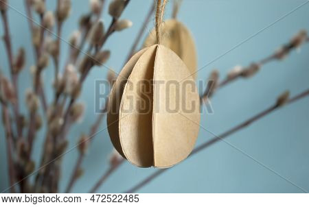 On A Blue Background Paper Eggs Hang On Willow Branches For Easter. Diy Crafts Bulky Paper Eggs As A