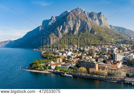 Sunny Aerial Cityscape Of Lecco Town On Spring Morning. Picturesque Waterfront Of Lecco Town Located