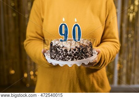 Happy Ninetieth Birthday. Woman Holding Fresh Delicious Birthday Cake With Burning Candle Number 90,
