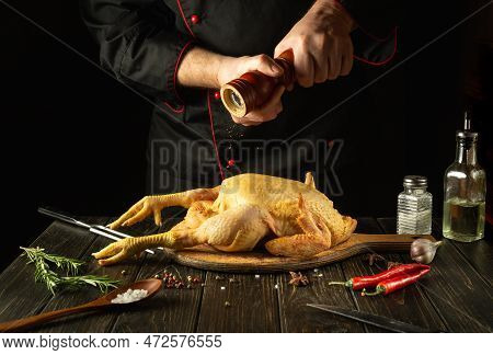 The Chef Prepares Raw Rooster In The Kitchen. The Cook Adds Black Pepper To The Cock Before Frying. 