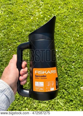 Germany - Apr 13, 2022: Pov Male Hand Holding Fiskars Spreader For Garden Use - Green Garden Backgro