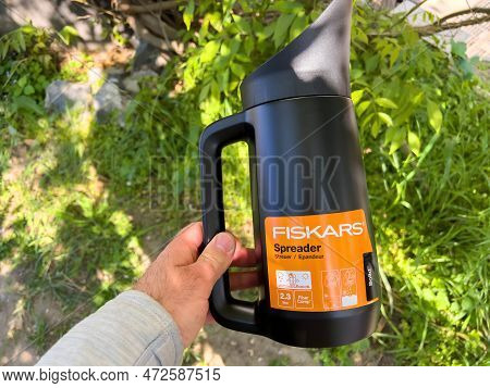 Germany - Apr 13, 2022: Pov Male Hand Holding Fiskars Spreader For Garden Use - Green Trees Garden B