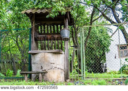 Old Well With Iron Bucket On Long Forged Chain For Clean Drinking Water