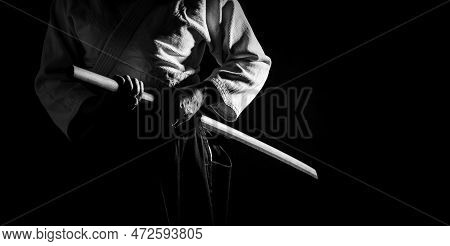 A Person In Black Hakama Standing In Fighting Pose With Wooden Sword Bokken In Black And White. Shal