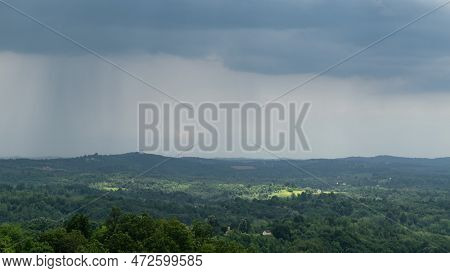 Cloudburst Over Hilly Countryside And Sun Spots On Forest And Scattered Village