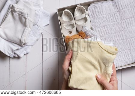 Female Hands Put Children's Clothes, Shoes And Toys Into A Box. Second Hand, Clothing Recycling Conc