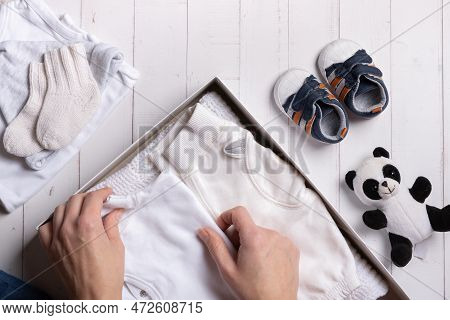 Female Hands Put Children's Clothes, Shoes And Toys Into A Box. Second Hand, Clothing Recycling Conc