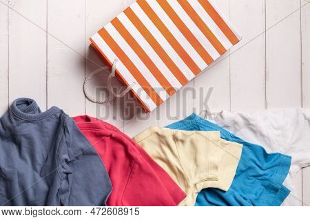 Colorful Clothing And Shopping Bag On Wooden Background. Second Hand, Recycling Concept