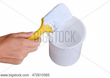 A Woman's Hand Holds A Brush Over A Jar Of White Paint, Isolated On A White Background. Yellow Brush