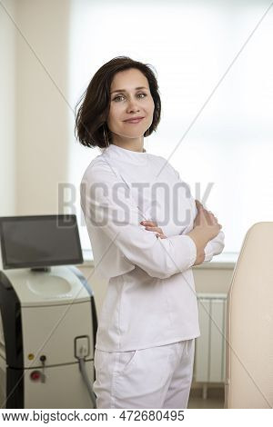 Positive Confident Female Doctor Posing In Doctor's Smock With Hands Folded In Front Against Intence