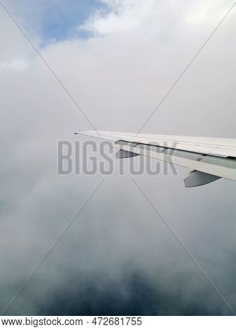 Plane Is Descending. Wing Of Airplane Through Clouds. Aerial View Seen Through Window Of Flying Aero