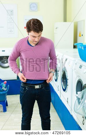 Genç adam bir Çamaşırhane, arka planda kirli çamaşırlarını çamaşır yıkama makineleri, o