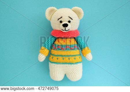Crochet Amigurumi Handmade Stuffed Soft Teddy Bear Toy In Colored Sweater On Blue Background. Handwo