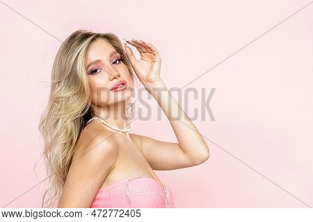 A Beautiful Attractive Woman With Blonde Hair In A Stunning Pink Dress On A Pink Background. Fashion