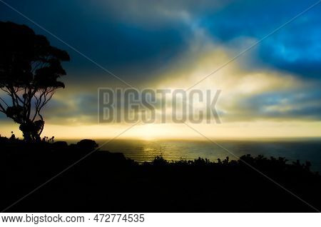A Dramatic Coastal Sunset On A Cloudy Day Turns The Sky A Brilliant Gold With Blue And Silver Accent