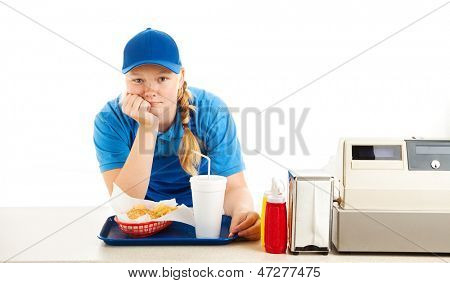 Teenage Arbeiter in einem Fast-Food-Restaurant gelangweilt und stützte sich auf den Zähler.  Weißer Hintergrund.