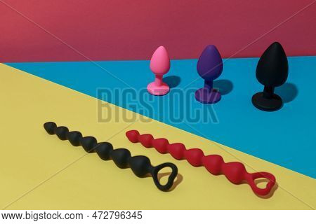 Different Buttplugs And Dildos For Anal Sex On Colored Background With Shadows. Sex Shop Concept