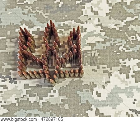 Coat Of Arms Of Ukraine Laid Out From Cartridges Against Background Of Camouflage Clothing. Cartridg