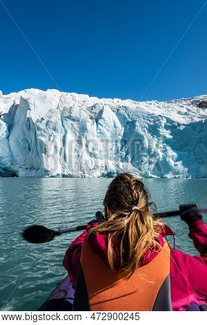 Young Woman Kayaking Mosevatnet Lake With Folgefonna Glacier In The Background, Visiting Norway