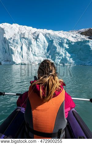 Young Woman Kayaking Mosevatnet Lake With Folgefonna Glacier In The Background, Visiting Norway