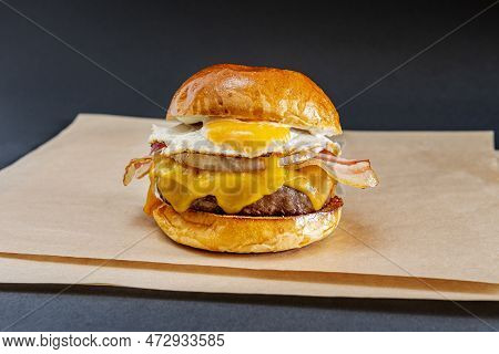 Great Beef Burger On Shiny Bun With Fried Egg, Sliced Bacon, Melted Dripping Cheddar Cheese, Sliced 