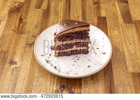Portion Of Three Chocolates Cake Seen From The Front On A White Plate And On A Table Of Oak Boards