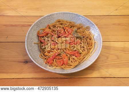 Tagliatelle In Teriyaki Sauce Sautéed With Lots Of Red And Green Peppers And Sesame Seed On Deep Gra