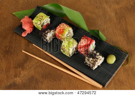 Velsmagende Maki sushi - Roll på måtten på brune baggrund