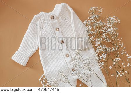 Jumpsuits For Newborns On A Beige Background Wihf White Flowers. Spring Clothes For Children