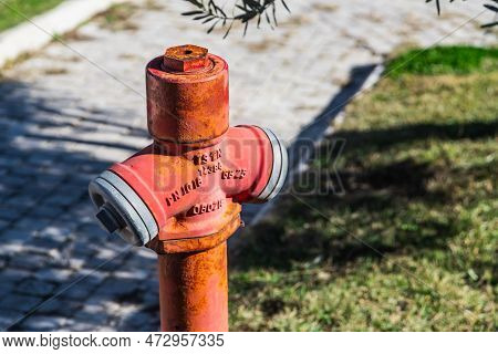 Close-up - Overhead Red Pressurized Fire Hydrant Against Green Bush Background