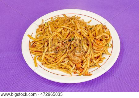 Plate Of Wok Noodles With Chicken Meat, Chopped Carrot, Zucchini With Skin On A Purple Background