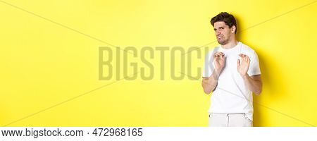 Digusted Guy Refusing And Grimacing, Looking At Something With Aversion, Standing Over Yellow Backgr