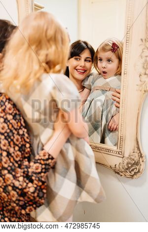 A Cute Little Girl In A Plaid Dress And Mom Looks In The Mirror And Primping.