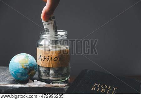 Saving Jars Full Of Money And Globe With Holy Bible For Mission, Mission Christian Idea. Hand Holdin