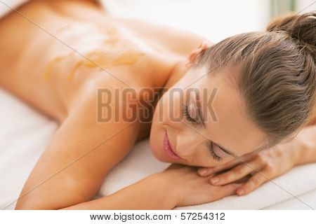 Young Woman With Honey On Back Laying On Massage Table