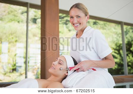 Brunette getting micro dermabrasion with therapist smiling at camera in the health spa