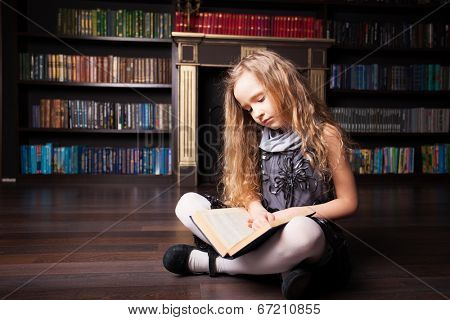 Girl reading book at home. Child in library