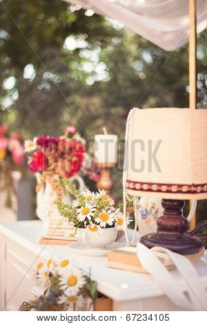 Shabby Chic Decor, White Table With Vintage Objects On It, Flowers Vase, Flower Pot An Opened Book