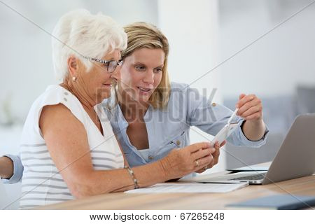 Homehelp with elderly woman using smartphone