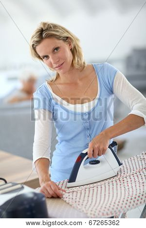Housekeeper at home ironing clothes for old woman