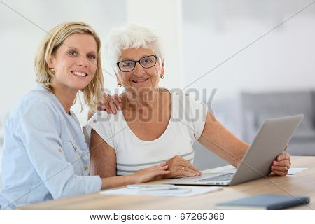 Homecarer with elderly woman using laptop computer