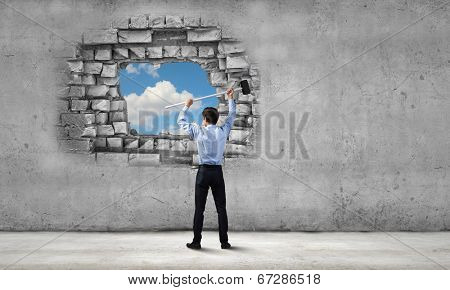 Young determined businessman with hammer in hands